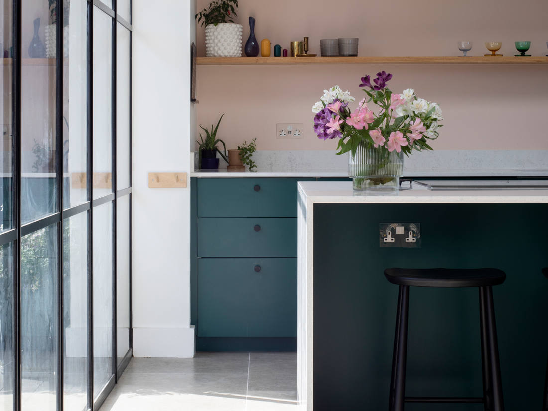 Kitchen with deep green units, pink walls and a steel-framed glazed screen, Hills Avenue